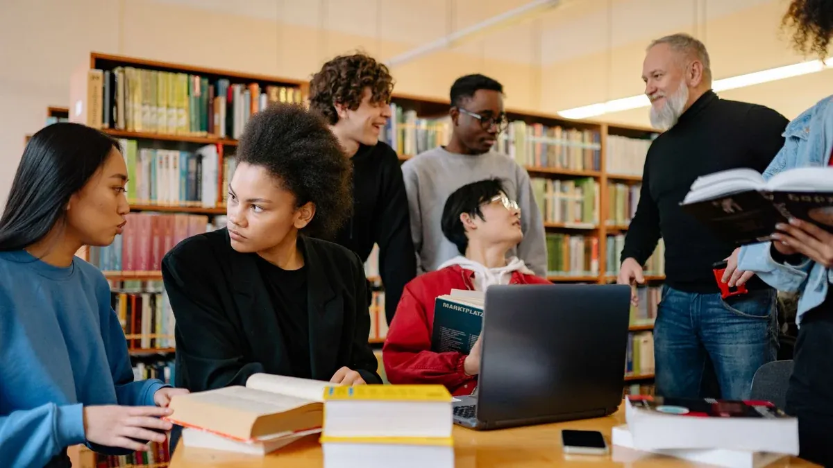 A diverse group of students studying together at a university library, engaged in discussion.