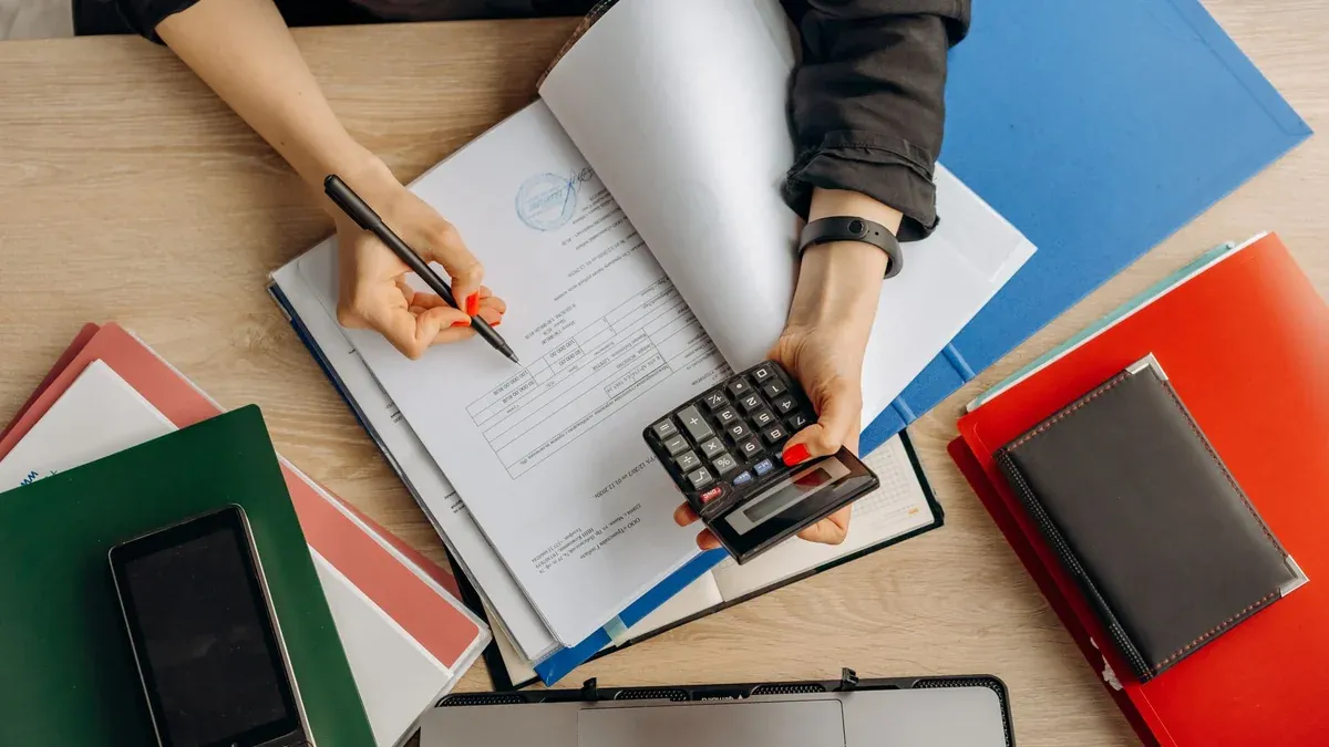 Accountant analyzing financial documents with a calculator on a desk, highlighting business tasks.
