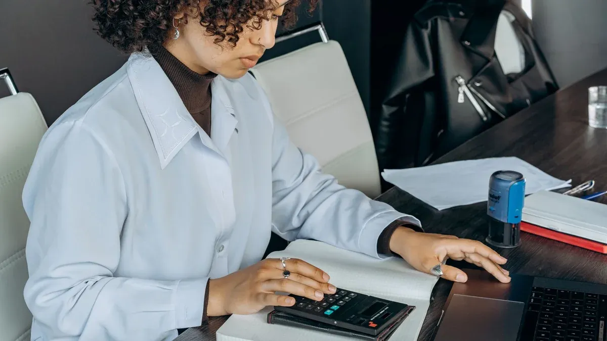 Young woman in office using a calculator for financial calculations.
