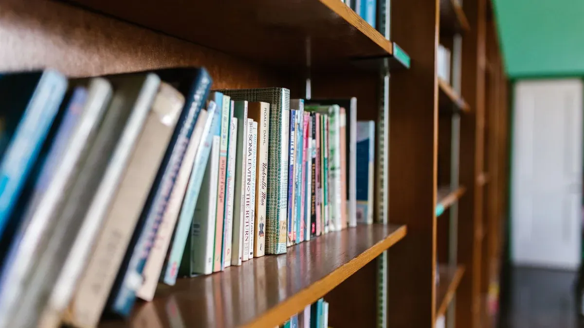 A wooden bookshelf filled with books in a cozy library setting, perfect for educational themes.