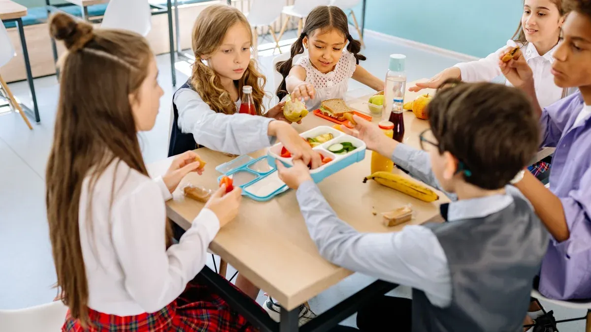 Group of diverse children having lunch in a school canteen, sharing and enjoying healthy snacks.