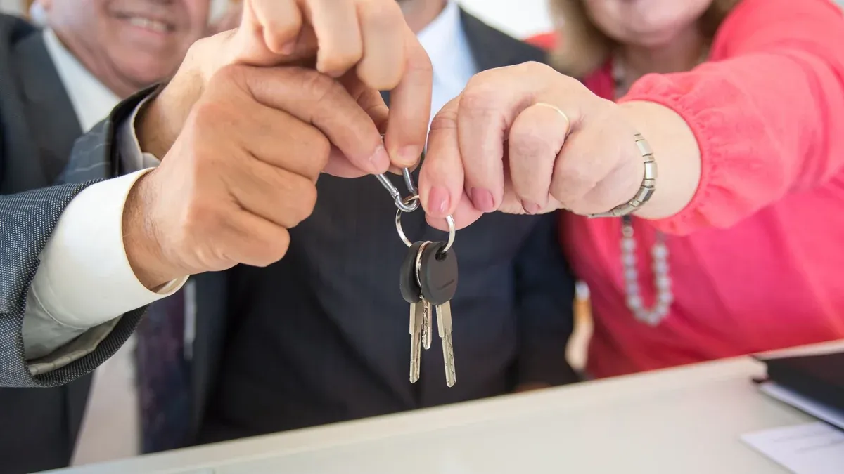 Business colleagues celebrating a successful deal with a handshake and keys exchange.