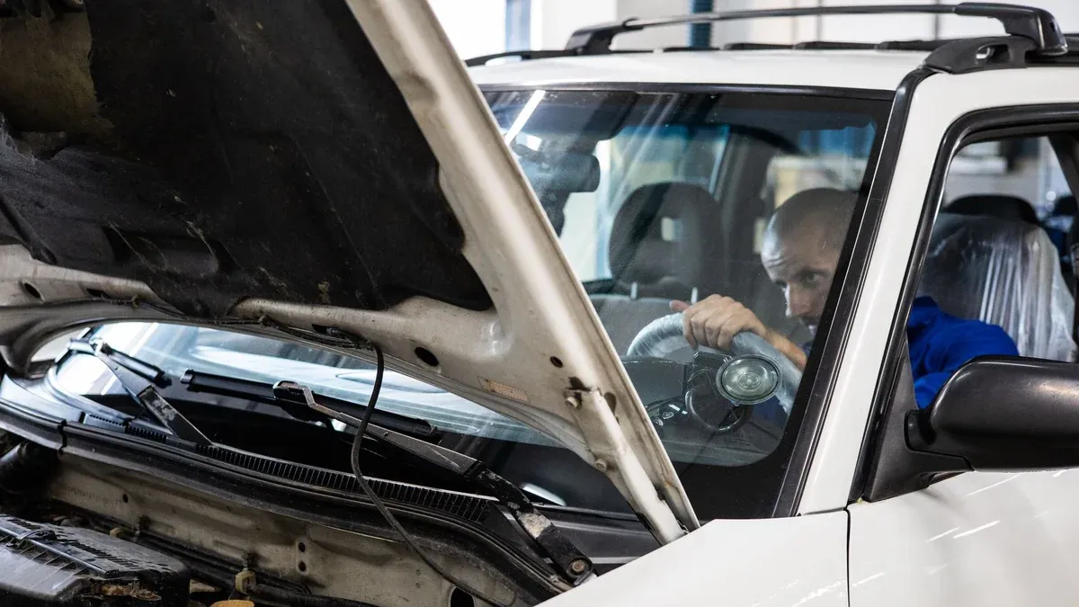 A mechanic performs a detailed inspection on a vehicle in a workshop setting.