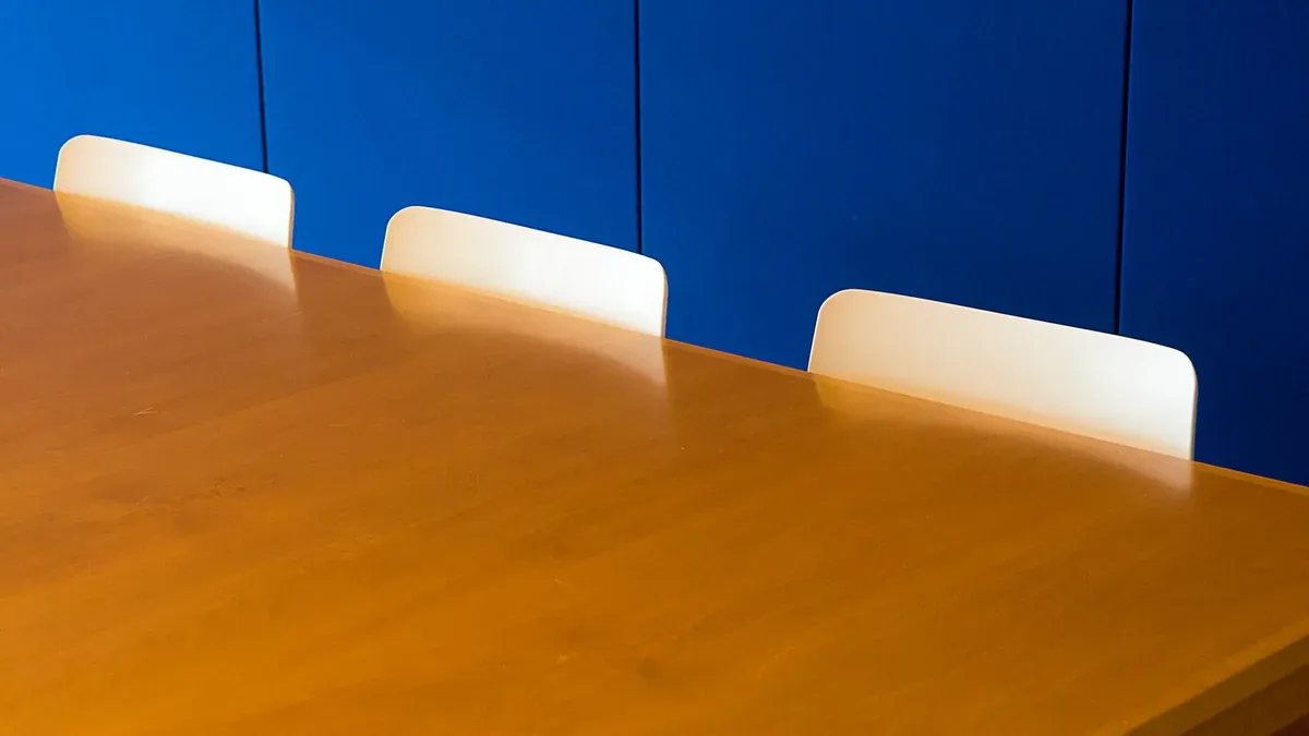 A clean and modern indoor meeting room with a wooden table against a blue wall.